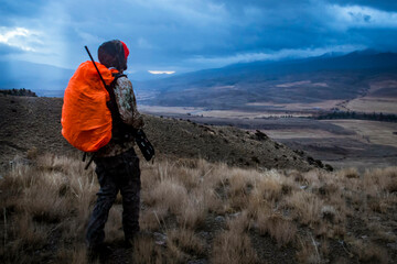 Deer hunter walking through Colorado backcountry at sunrise as thunderstorm approaches, Colorado, Colorado, USA