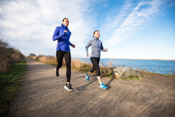 Women trail running together on a coastal path