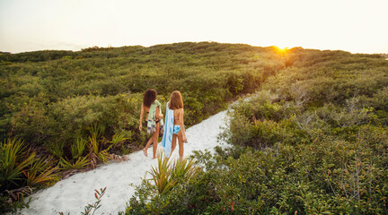 Two young woman walk along the sand dunes on a Florida beach.