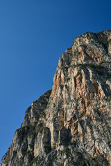 Gray rocks at high altitude. Alps top on blue sky. Rough rocky stones. The tops of the yellow peaks of the rocks. Red stones on a blue background.