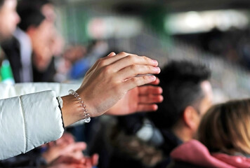 Hands of a fan during a football match in the stadium. Real life. Selective focus