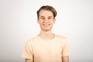 Portrait of a young blond guy in a yellow T-shirt on a white background.