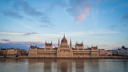 Panoramic view of Budapest Parliament from across Danube river, Hungary. Beautiful blue evening sky with pink clouds.