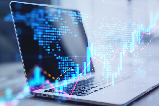 Close up of laptop on desktop with glowing candlestick forex chart map hologram on blurry background. Trade and market concept. Double exposure.