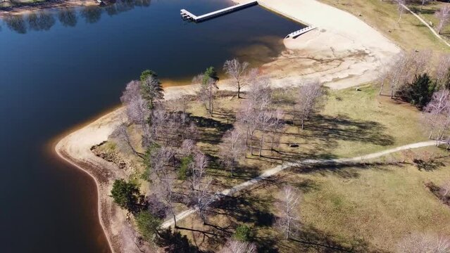 Plage naturel d'un &eacute;tang visible &agrave; partir d'un drone. Abord de lac dans un environnement naturel jonch&eacute; d'arbres divers.
