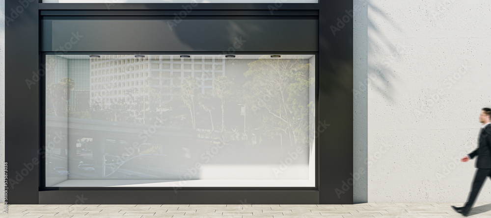 Poster man walking by sunlit wall background with place for your advertising poster near empty shop window 