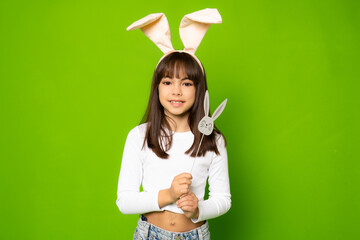 Photo of joyful brunette girl in toy rabbit ears smiling isolated over green background