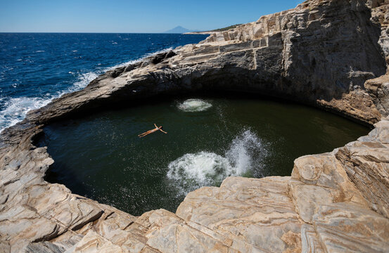 Woman swimming in cave pool on sunny day