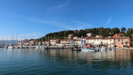 Fototapeta na wymiar Panorama sur le port de la presqu’île de Saint-Mandrier, sur la côte d’azur, près de Toulon dans le Var, avec le reflet des maisons colorées dans l’eau bleue de la mer Méditerranée (France)
