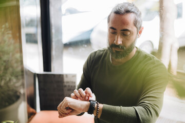 Man with beard checking time on wrist watch