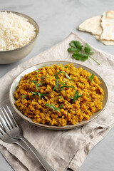 Homemade Red Lentil Dahl with Rice and Cilantro on a gray surface, side view.