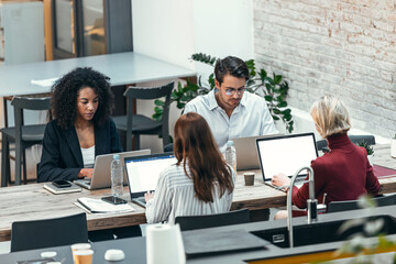 Businessman and businesswomen working on laptop at desk