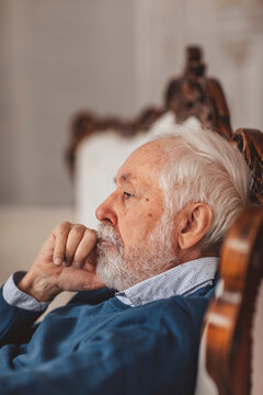 Contemplative senior man sitting on chair at home
