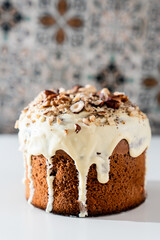 A cake with white chocolate glaze and nuts on a light background. Easter dinner, traditional dishes