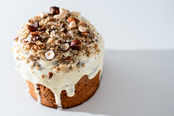 Easter holiday. Raisin cake with white chocolate glaze and nuts on a light background