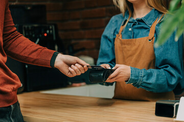 Hand of customer paying through credit card at cafe