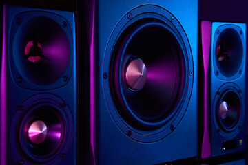 Two sound speakers and subwoofer on dark background with neon lights. Set for listening music....