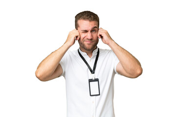 Young caucasian man with ID card isolated on green chroma background frustrated and covering ears