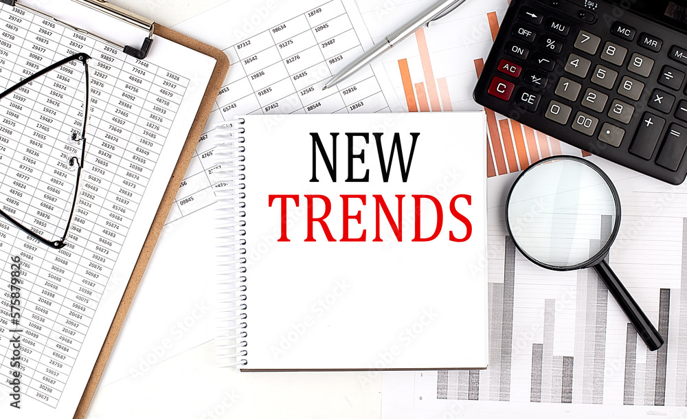 Poster NEW TRENDS text on notebook with clipboard and calculator on a chart background