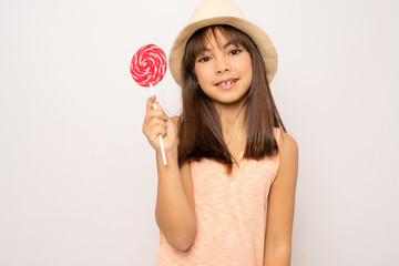 beautiful cute little child girl eating lollipop standing isolated over white background.