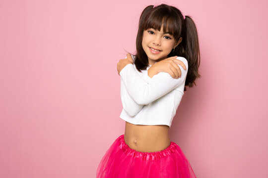portrait image with smiling little brown-haired girl. Concept happy and beauty kid with good healthy on pink background, eight year child looking at camera and posing