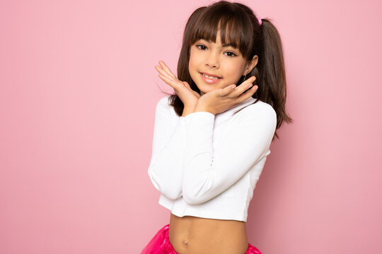 portrait image with smiling little brown-haired girl. Concept happy and beauty kid with good healthy teeth for dental on pink background, eight year child looking at camera and posing