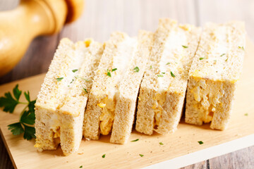 Egg salad sandwiches on wooden board.