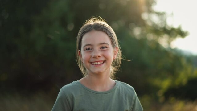 Video of a beautiful little girl laughing when having fun in summer in nature.