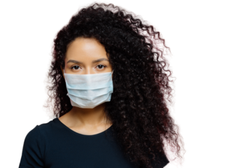Serious dark skinned young woman being on self isolation at home, wears protective medical mask, being on quarantine at home, dressed casually, poses against pink background. Coronavirus disease