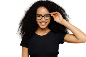Lovely young African American woman grins at camera, keeps hand on rim of spectacles, glad to hear good news, dressed in casual black t shirt, isolated over brown background. Happiness concept
