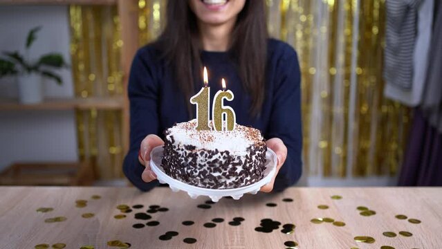 Holidays and celebration concept. Excited woman celebrating 16 birthday, blowing candle number sixteen on cake, wearing party cake and having fun on camera. Point of view or POV.