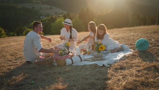 Happy family with children having picnic in park.