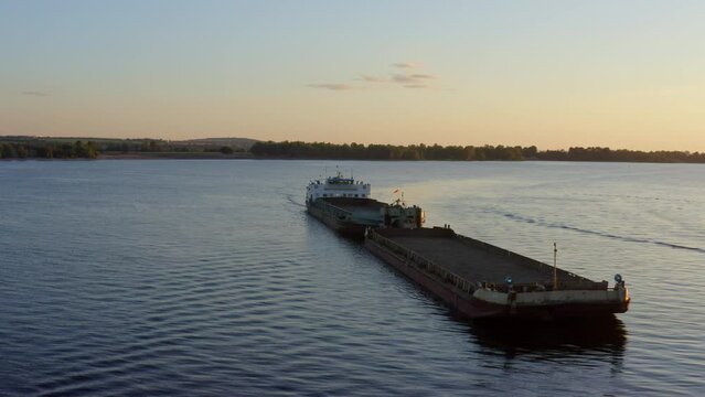 Flight of the drone over the ship. Beautiful sunset and coastline. The barge ship floats on the water