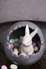 photo in a large gray decorative egg lies a lot of colorful decorative small eggs and a white rabbit
