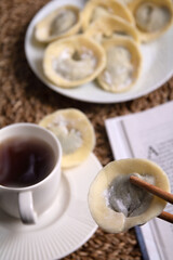 photo lots of chocolate sweets in the form of dumplings lying on a plate next to a book and a coffee cup with a drink