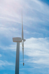 Close-up of the top of a wind turbine against a blue sky. A hopeful eco-friendly backdrop on the theme of generating energy using renewable resources.