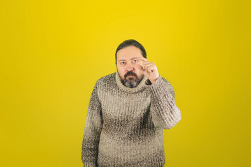 An adult man in a warm sweater shows a small size with his fingers. A template for a layout indicating the size or adding a small object to the hand.