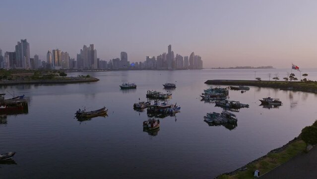 Slow motion drone shot of Panama City in the morning at mercado de marisco with view of the city and skyline ion the background and fishermen boats in front while orbit