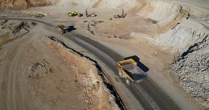 Large quarry dump truck transporting ore on open pit mine, aerial slow motion shot