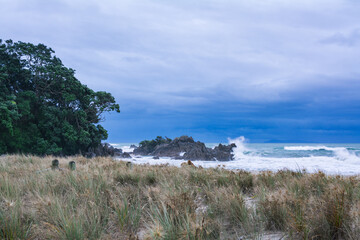 Angree waves crushing over coastal rocks on a stormy day. Powerful wave dramatically crushing on the beach. Mt Maunganui, New Zealand