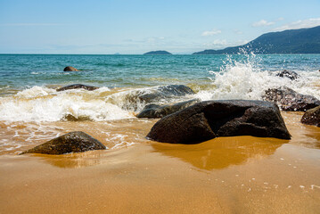 Ocean waves crashing on the rocks surrounding the quiet beach of Ilhabela