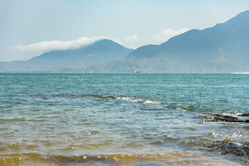 Landscape of the blue sea of Ilhabela in a cloudy day surrounded by the mainland mountains, São Paulo