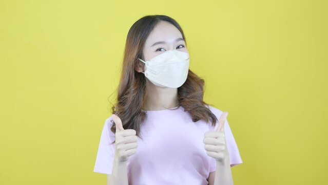 Asian woman in mask showing great thumbs up