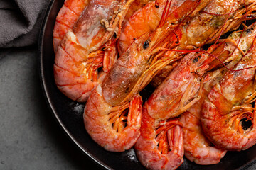 Close-up of giant argentinian red prawns, grilled. Black plate. Dark background.