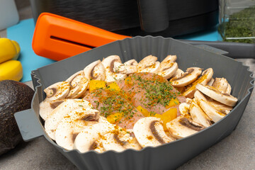 Two Chicken Breasts coated with herbs and spices alongside mushrooms and diced peaches ready for the Air Fryer economic cooking