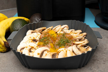 Two Chicken Breasts coated with herbs and spices alongside mushrooms and diced peaches ready for the Air Fryer economic cooking