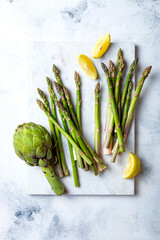 Bunch of fresh green asparagus on marble board. Green asparagus seasonal spring cooking. Overhead view, white background