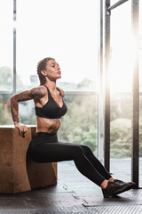 Portrait of young attractive muscular woman doing box squat at gym