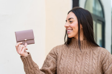 Young woman holding a wallet at outdoors with happy expression