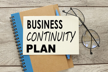 BCP Business continuity plan text on paper on a wooden background.near glasses